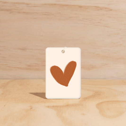 The Commonfolk air freshener, with a heart shape cut out in the center on a white background.