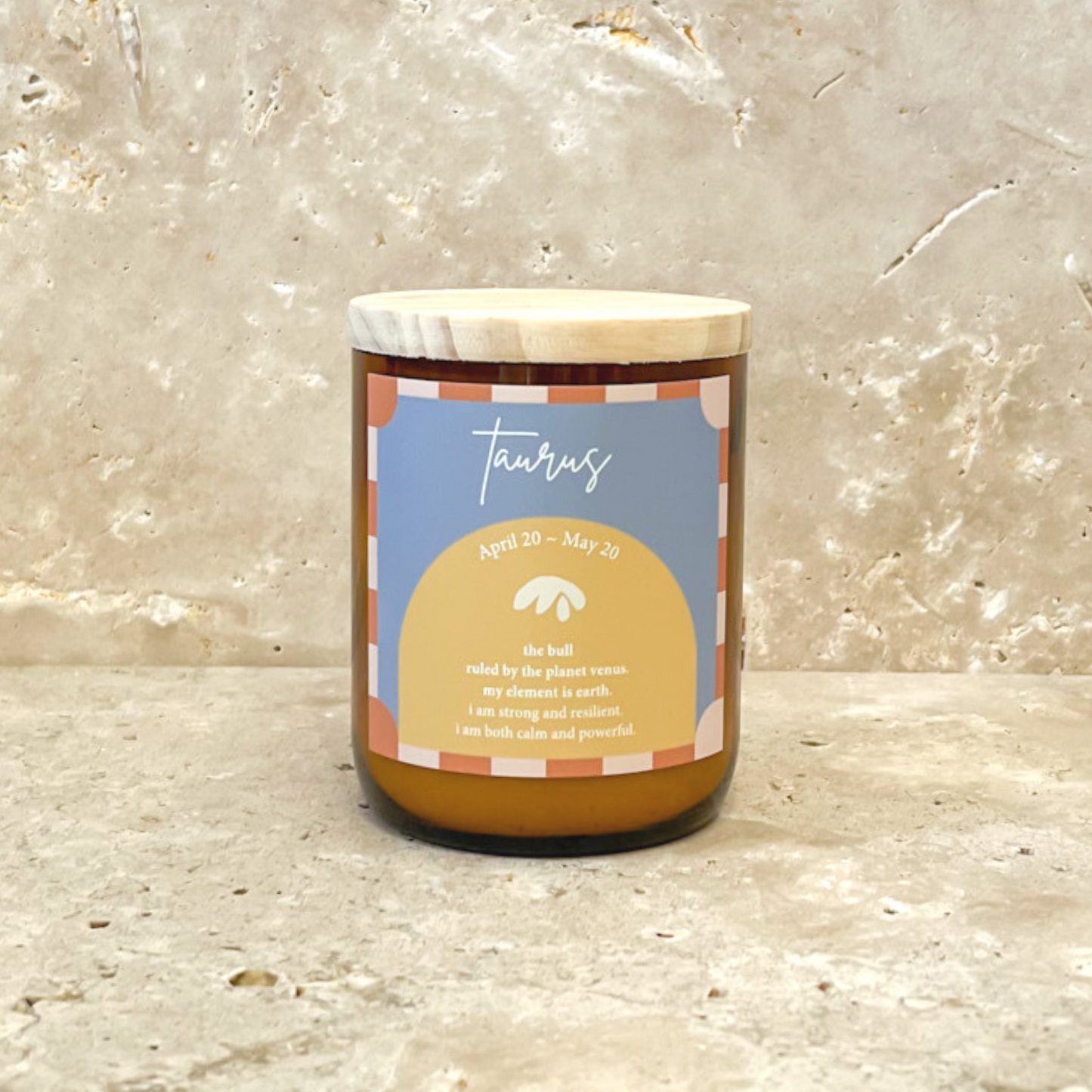 The Commonfolk scented candle has a label indicating it is a Taurus Zodiac Colour Candle. The label features a yellow and blue color scheme with text and an illustration of a bull's head.
