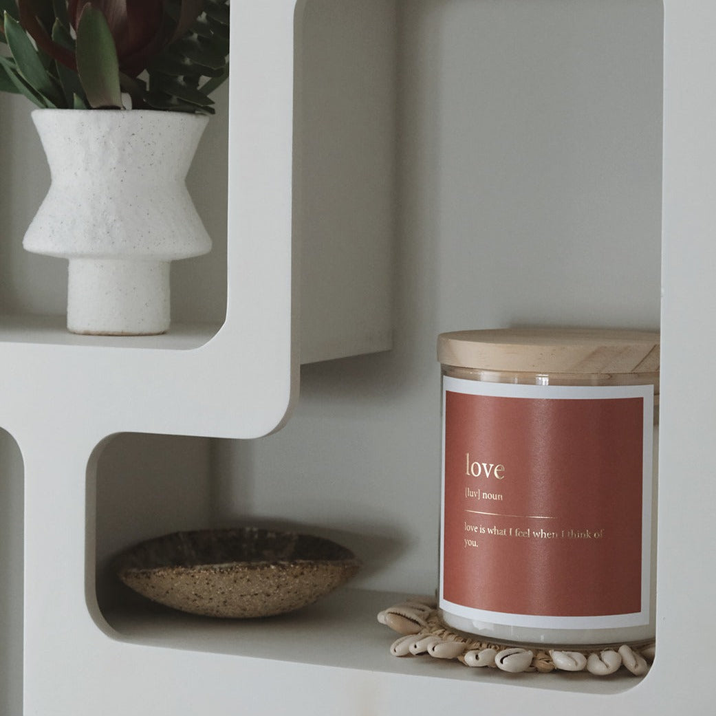 A candle on a shelf beside a decorative vase, creating a cozy and inviting atmosphere.