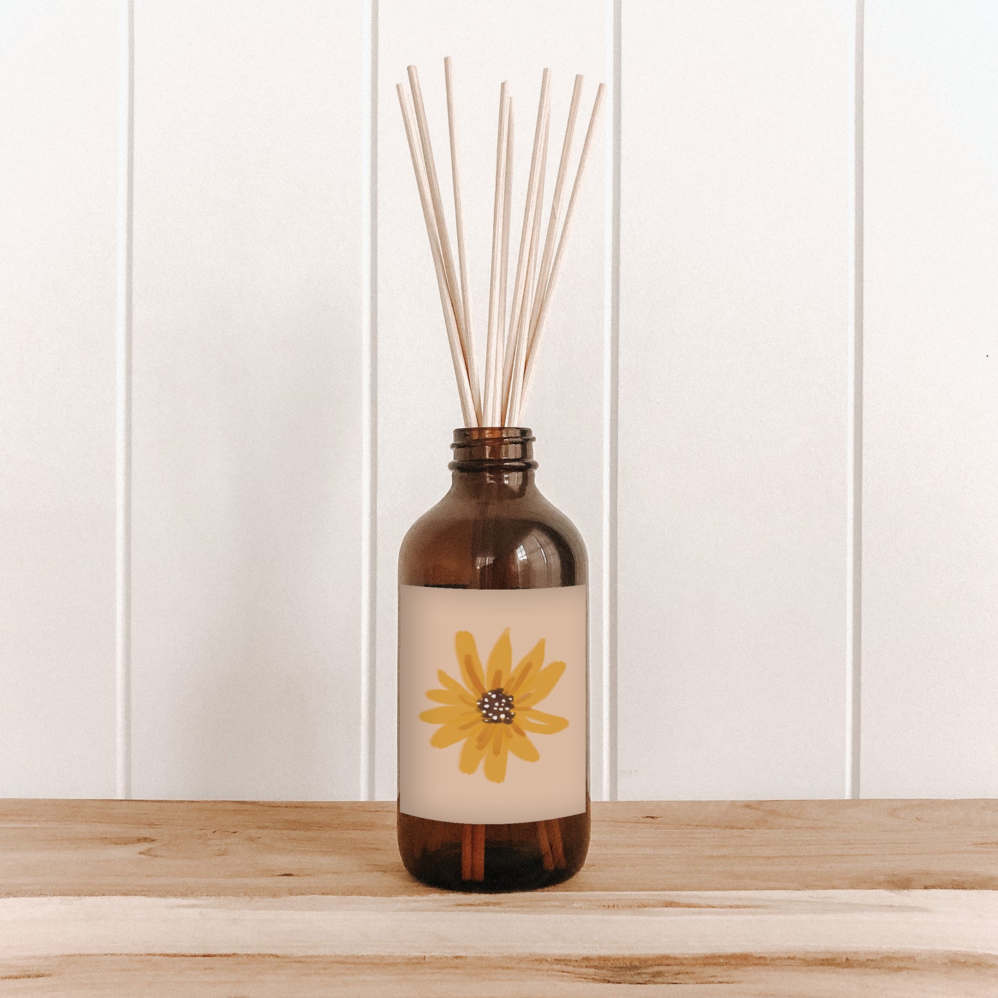 The Commonfolk room diffuser with natural bamboo reed sticks in a brown bottle features a yellow flower label on the front.