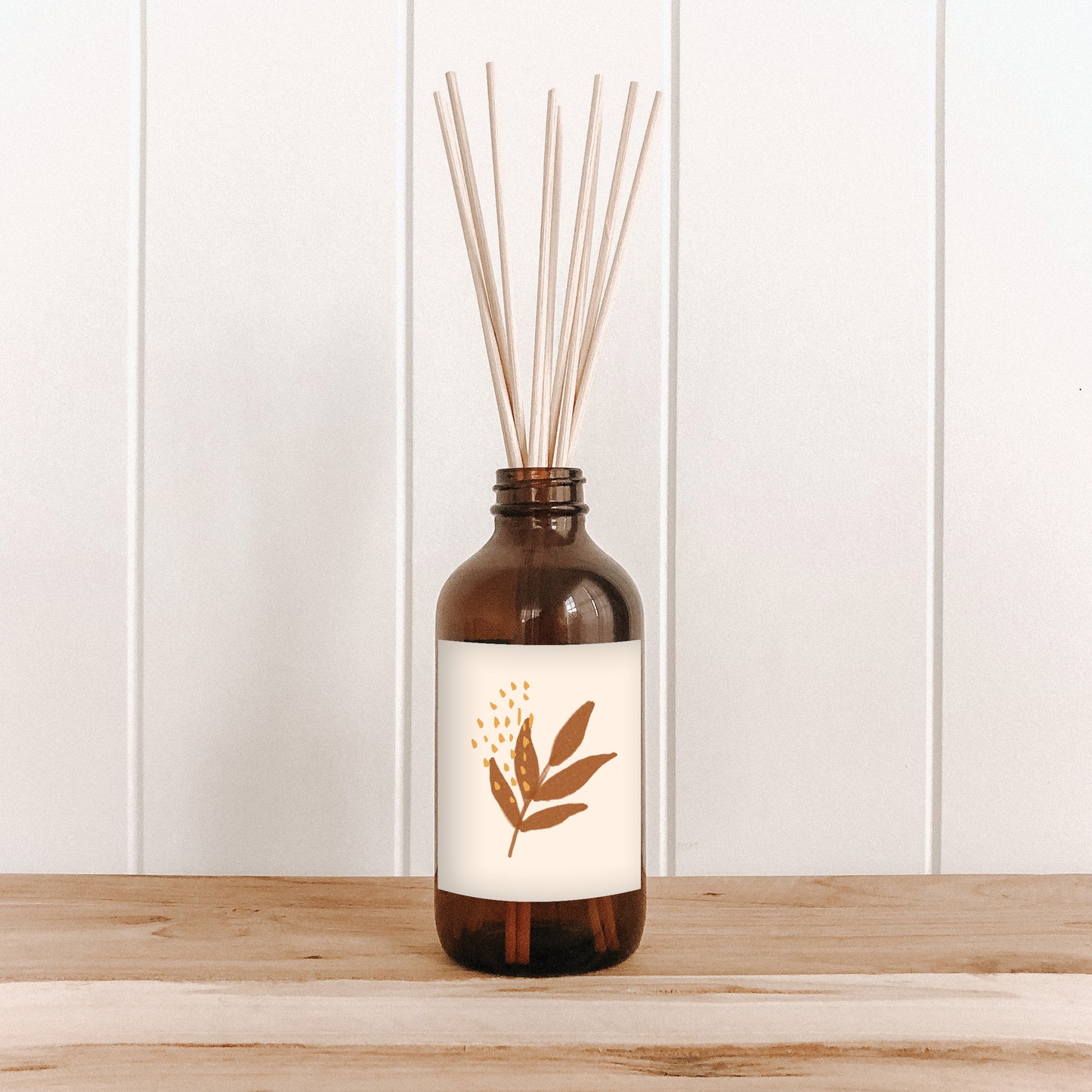 The Commonfolk room diffuser with natural bamboo reed sticks in an amber glass bottle features a white label with a leaf design.