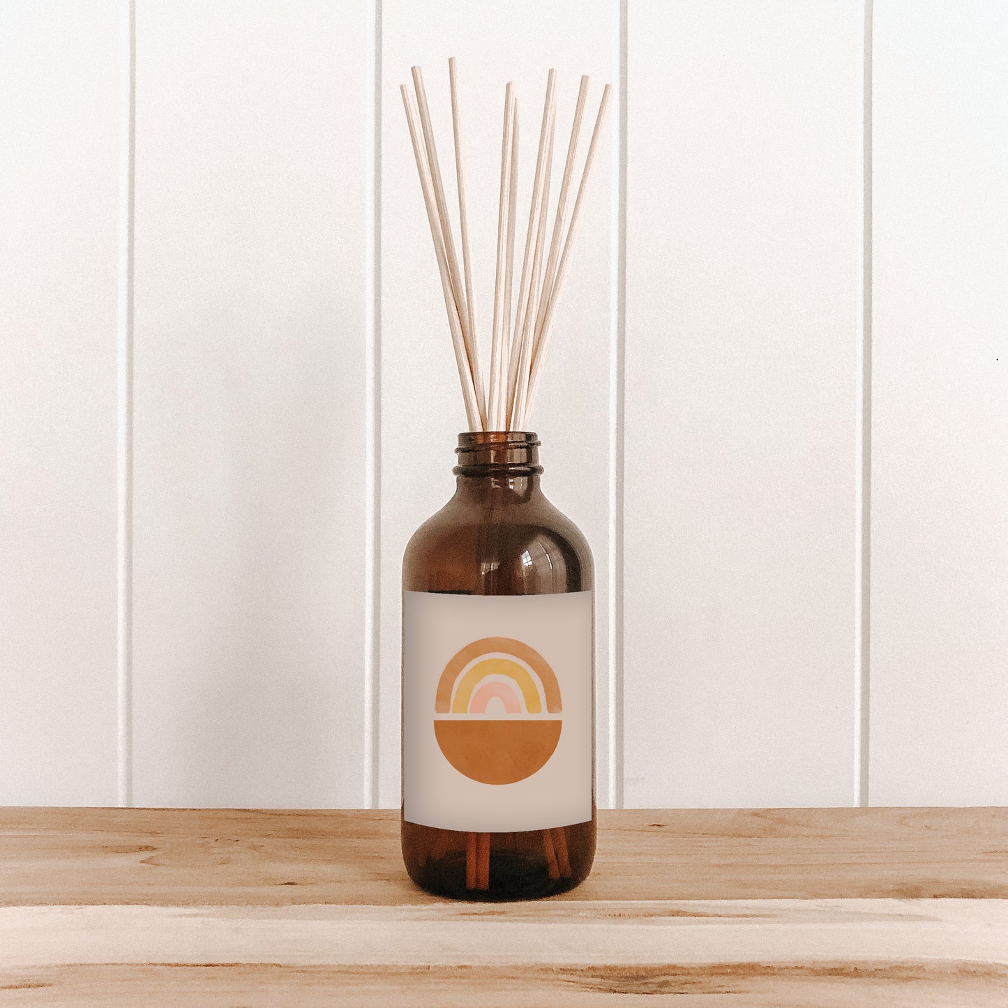 The Commonfolk room diffuser with natural bamboo reed sticks in an amber glass bottle features a label with a rainbow motif.