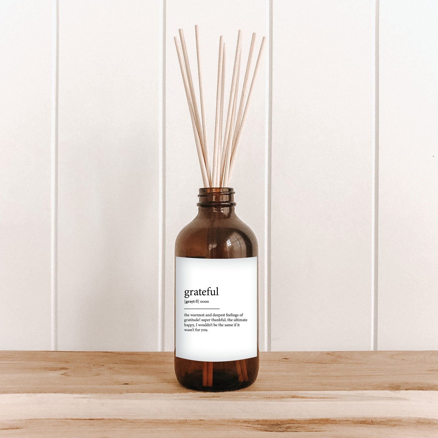 The Commonfolk room diffuser on a white wooden background, with text that reads 'grateful' on a white label.