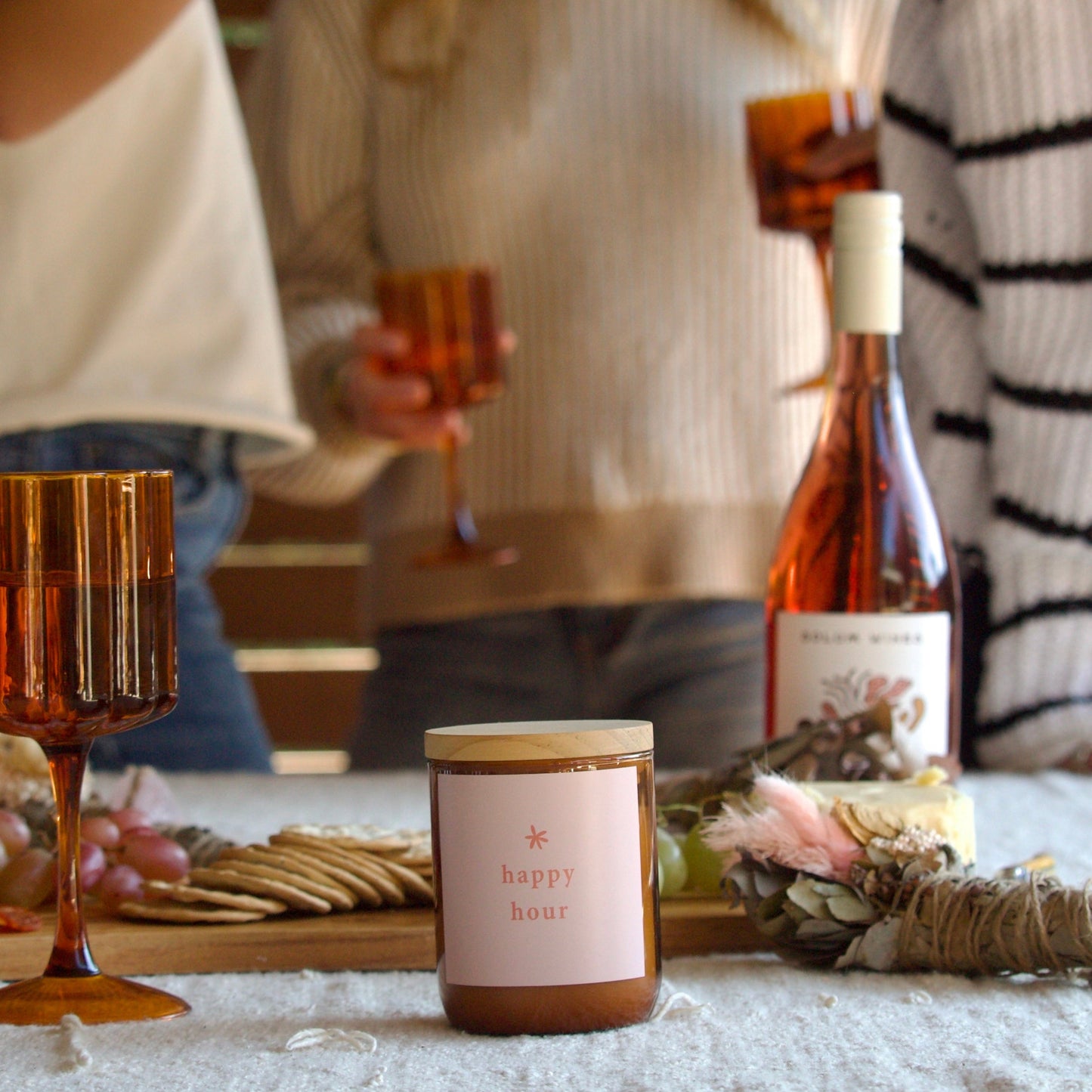 People enjoying a festive gathering with a bottle of wine and a candle on a table.