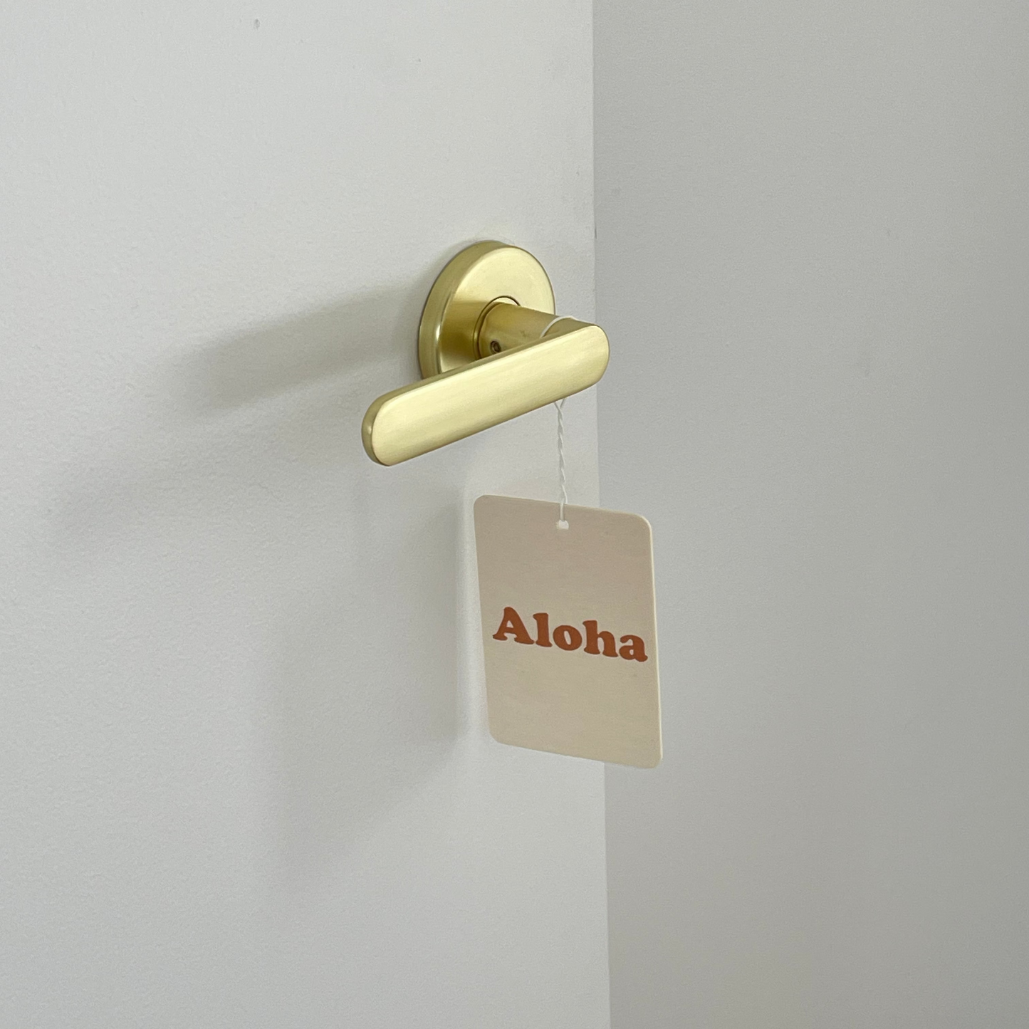 Gold door handle on a white door with an air freshener hanging.