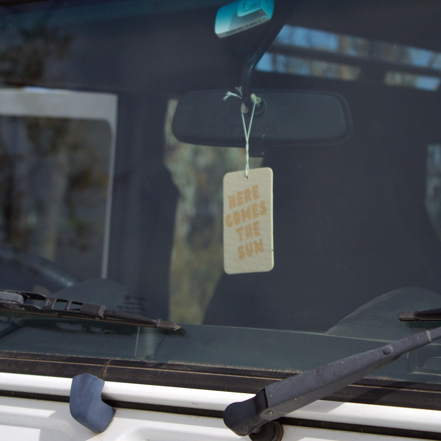 Car with a 'Here Comes the Sun' air freshener on the windshield