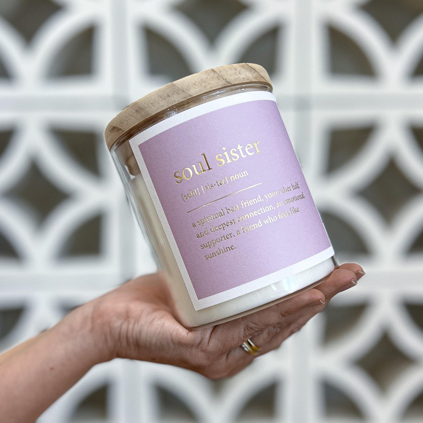 A woman holds a candle labeled "soul sister," symbolizing friendship and connection.