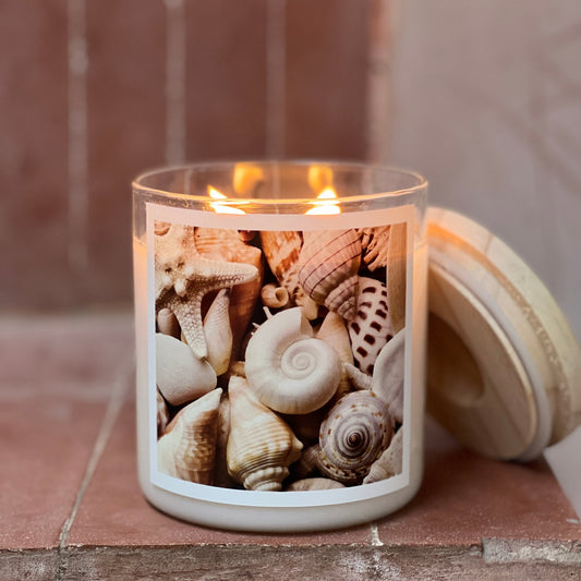 A candle decorated with various shells sits atop a table, adding a touch of beach-inspired charm to the room.
