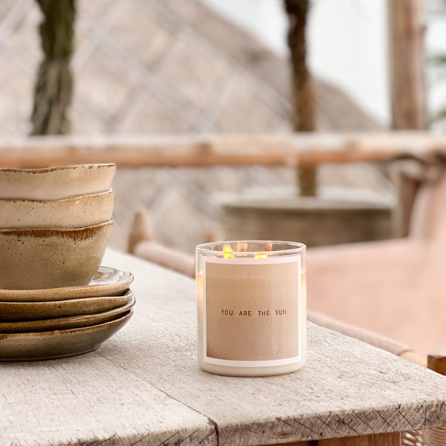 Candle with 'You are the sun' message on a wooden table outdoors