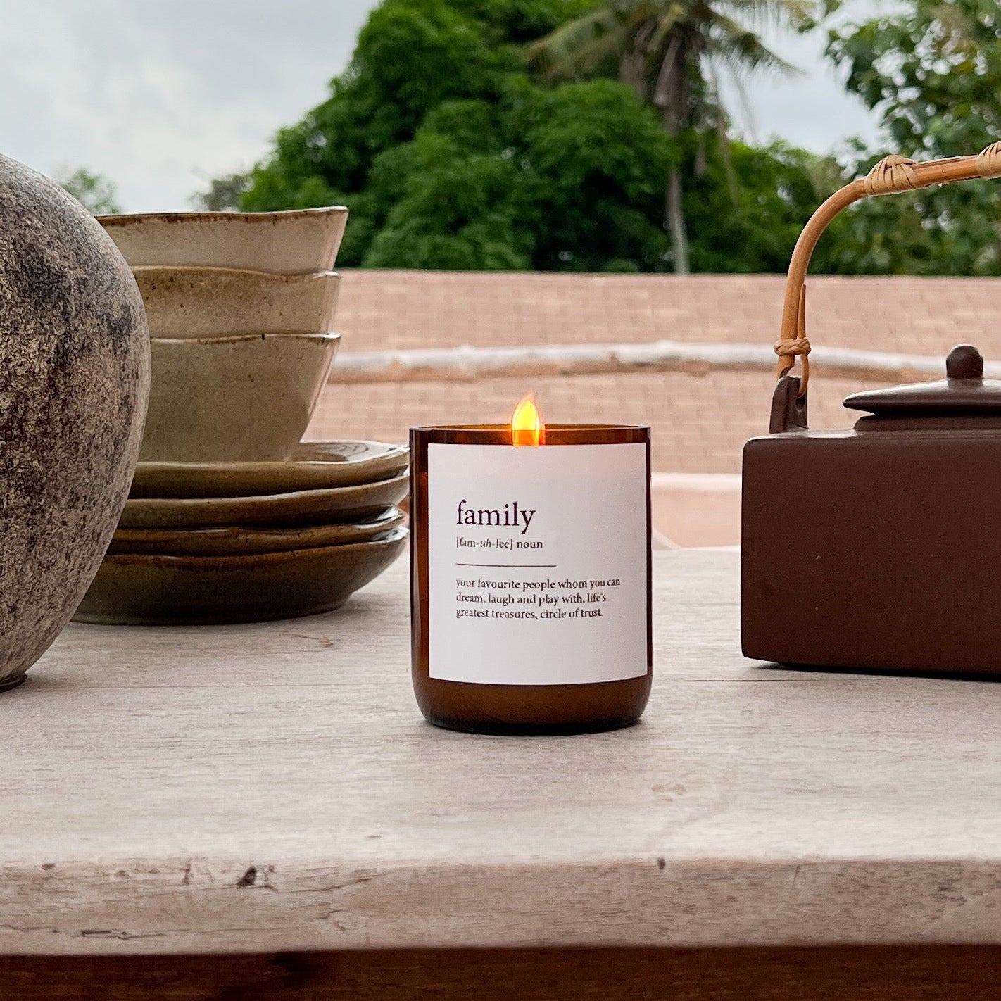 Candle labeled 'family' on a wooden surface with natural background
