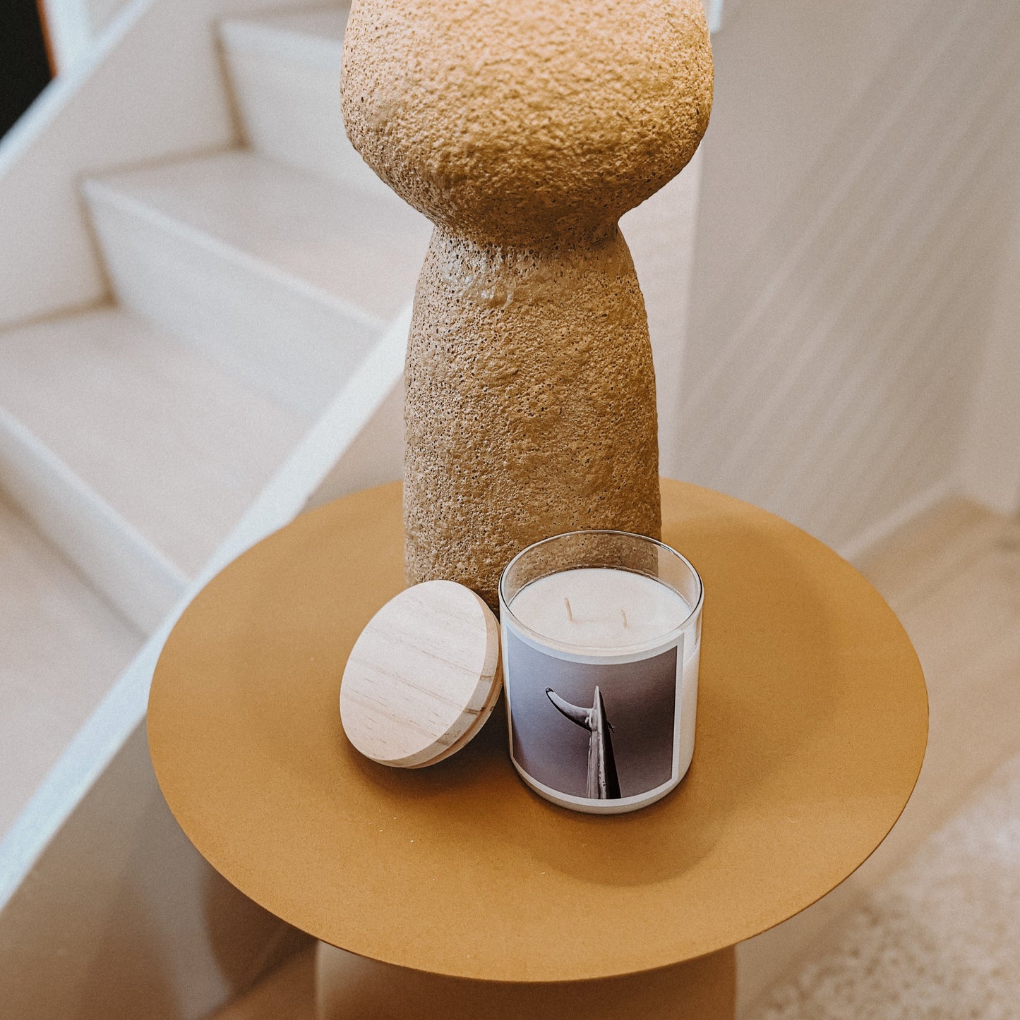 Decorative lamp with a textured base on a small round table next to a staircase.