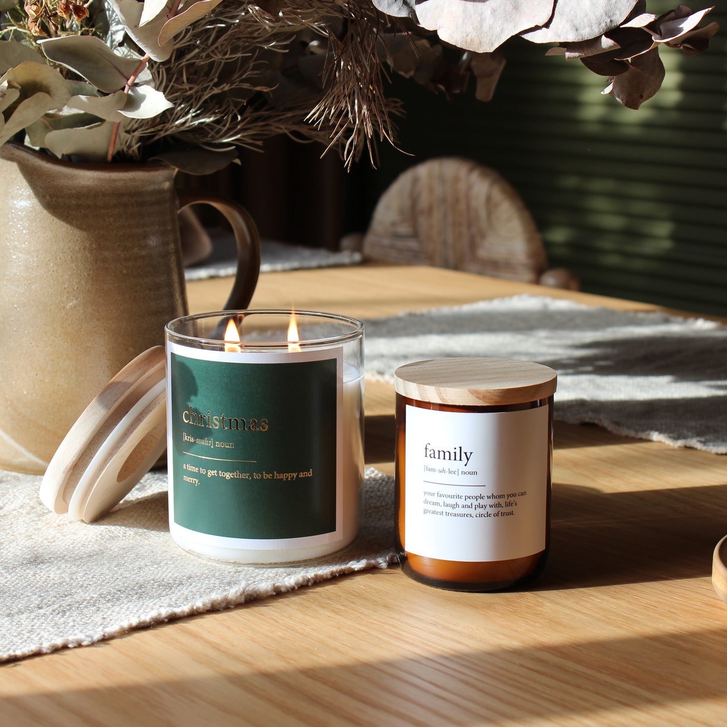 A candle placed on a table beside a decorative vase filled with flowers.
