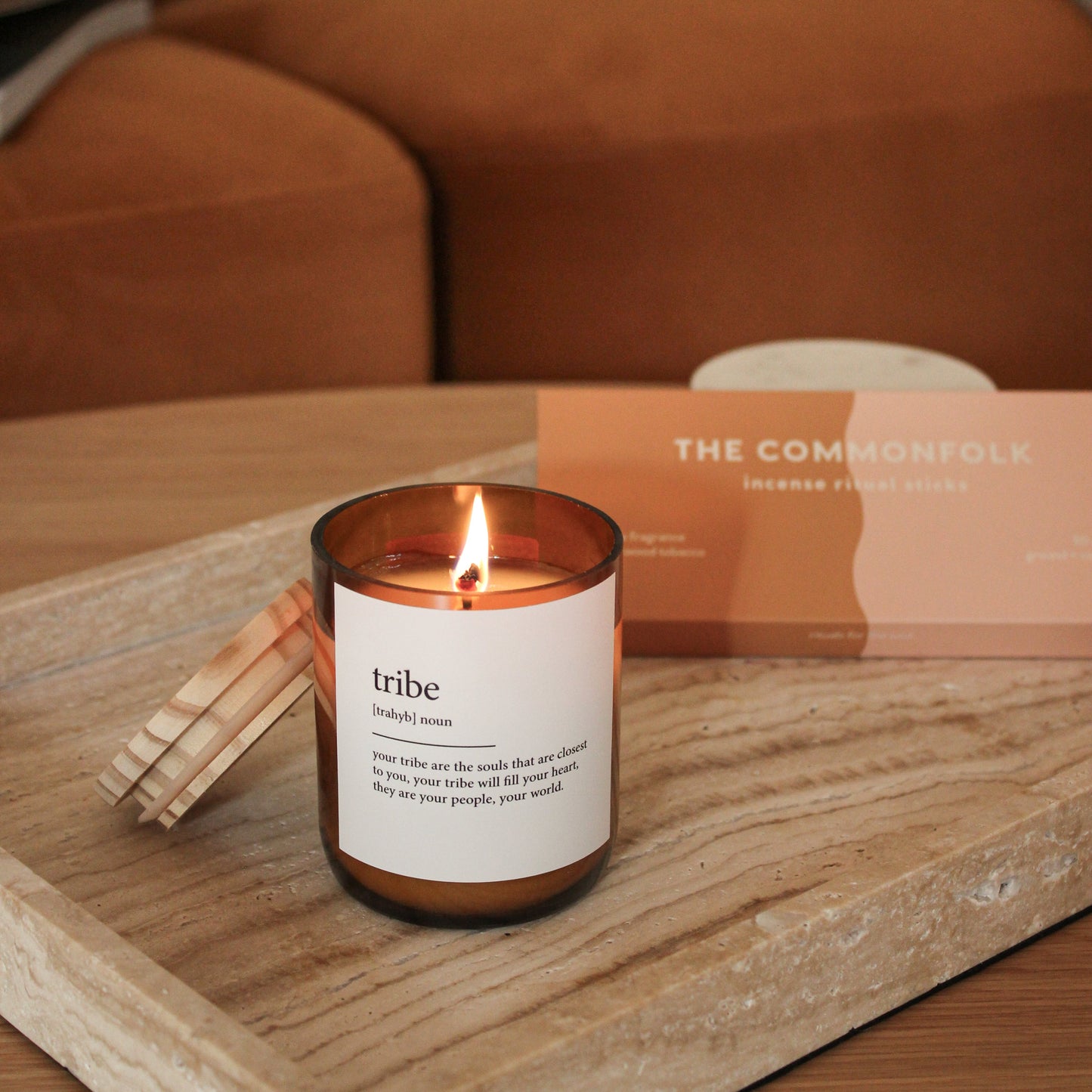 Candle labeled 'tribe' on a wooden tray with a blurred background