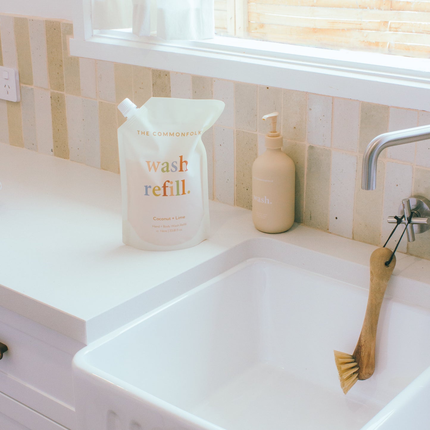 A sink with a wash refill pouch and a bottle against a neutral background.