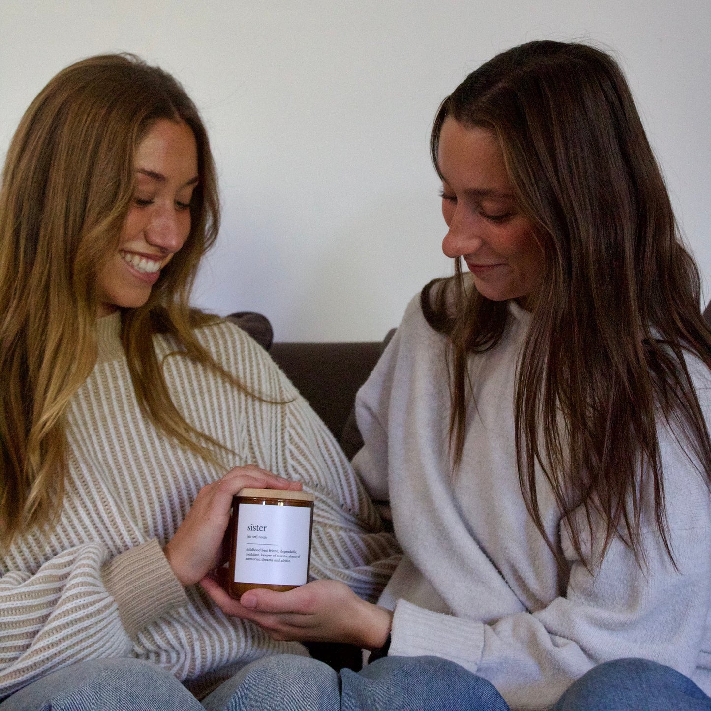 Two people holding a jar labeled 'sister' in a cozy indoor setting.