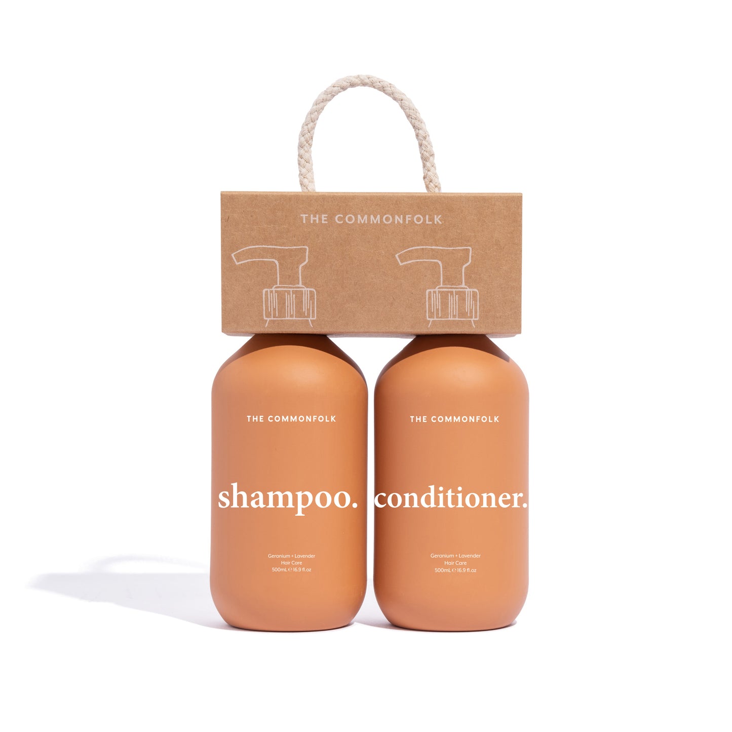 The Commonfolk shampoo and conditioner are packaged in a recycled Kraft carry caddy with a rope handle. The bottles are both 500ml and matte terracotta with white labeling, and the caddy has an illustration of a dropper bottle.