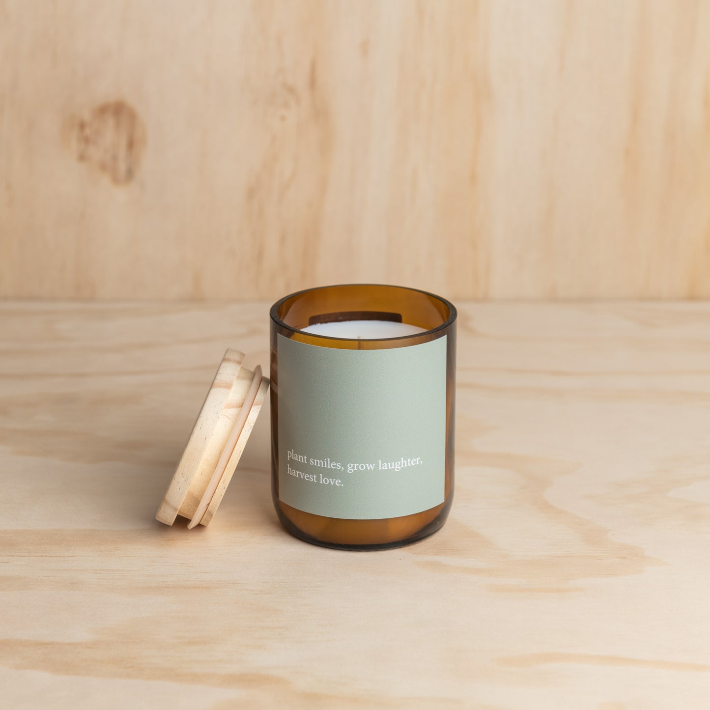 A candle rests on a wooden table, with a matching wooden background enhancing the natural ambiance.