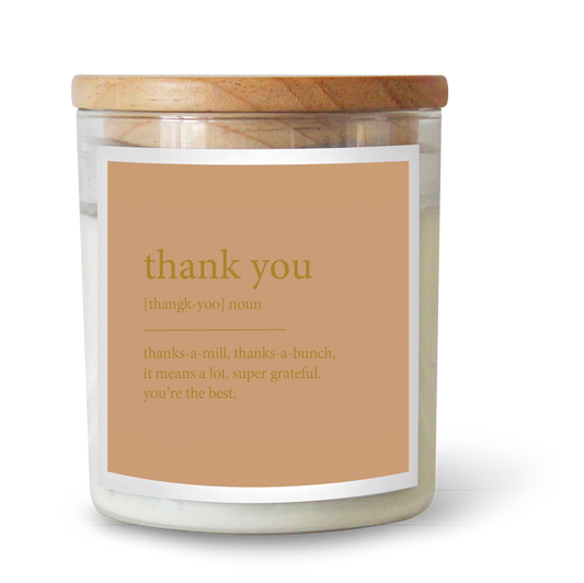 The Commonfolk scented candle has a wooden lid and a label that reads 'thank you' in various fonts, indicating a gratitude theme.