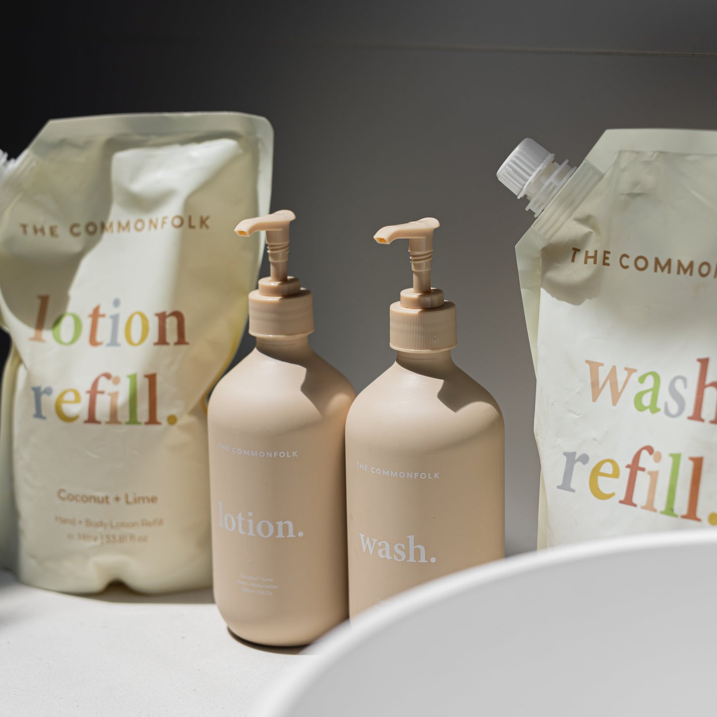 Displaying two bottles and two pouches of wash and lotion, emphasizing a clean and organized bathroom setting.