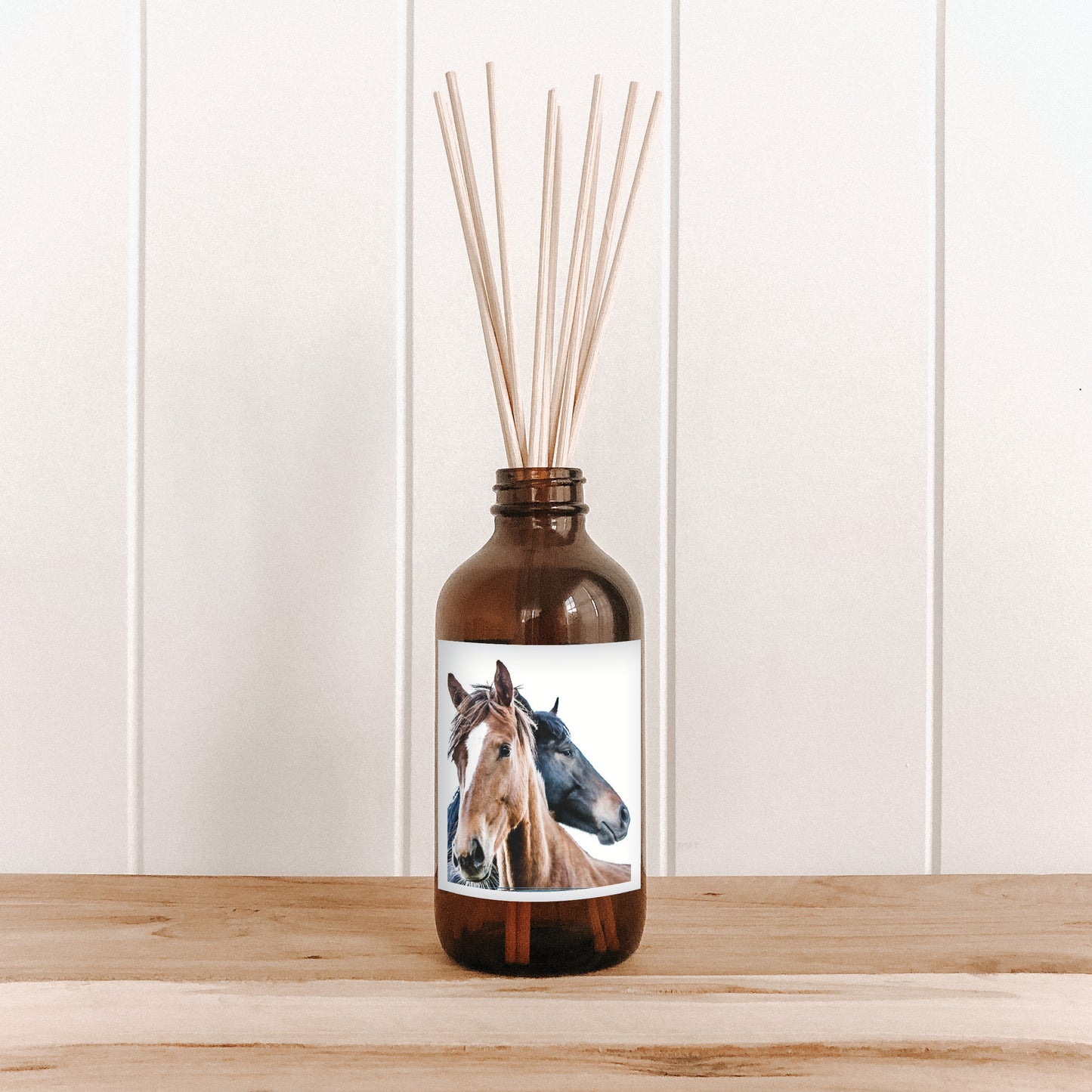 The Commonfolk room diffuser with a horse design label on a wooden surface and white paneled wall background.