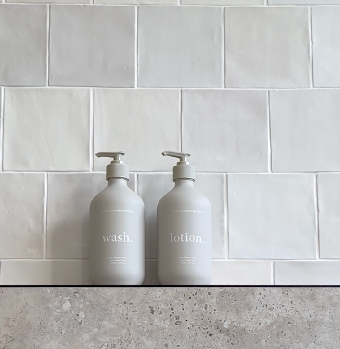 Two soap bottles are placed on a counter beside a wall, creating a clean and organized appearance.
