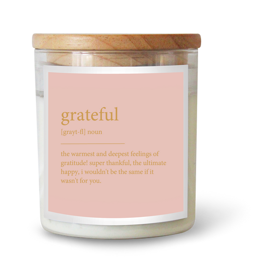 The Commonfolk scented white candle with a wooden lid and a label that reads 'grateful' alongside the definition 'the warmest and deepest feelings of gratitude'.