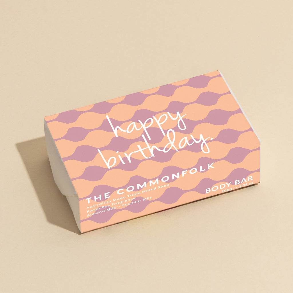 The Commonfolk 200g body bar soap with 'Happy Birthday' text, predominantly in pink and purple colors.