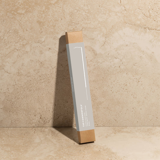The Commonfolk scented incense ritual sticks pack is placed upright on a textured surface, with the branding visible on the box. The box is gray with brown on both sides.