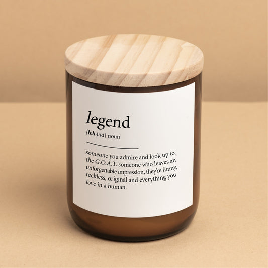 The Commonfolk scented candle with a wooden lid and amber jar, labeled 'legend' with the definition 'someone you admire and look up to'.