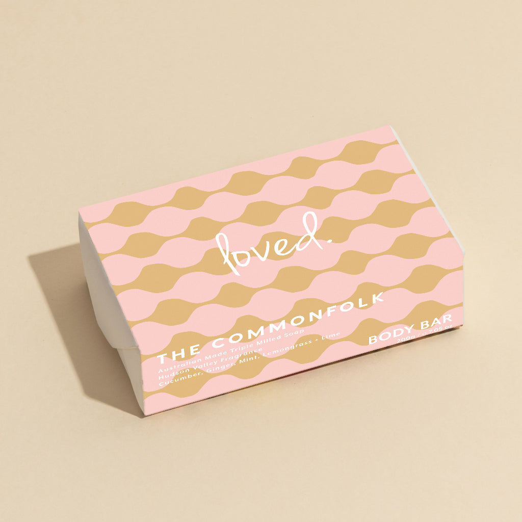 The Commonfolk 200g body bar soap is pink and gold, patterned with the text 'loved' on it.