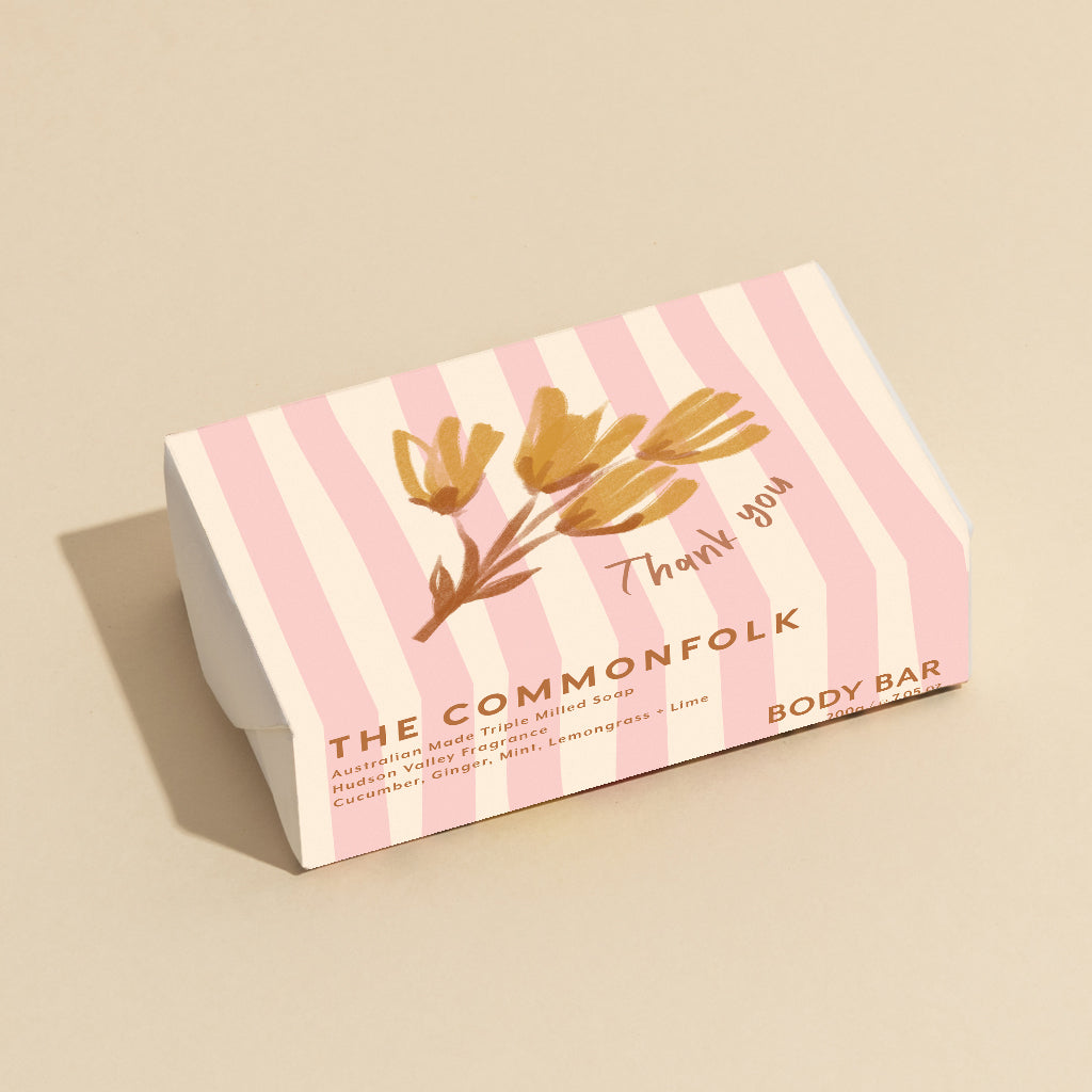 The Commonfolk 200g body bar soap with pink stripes and a floral design, labeled 'Thank you', is placed on a beige background.