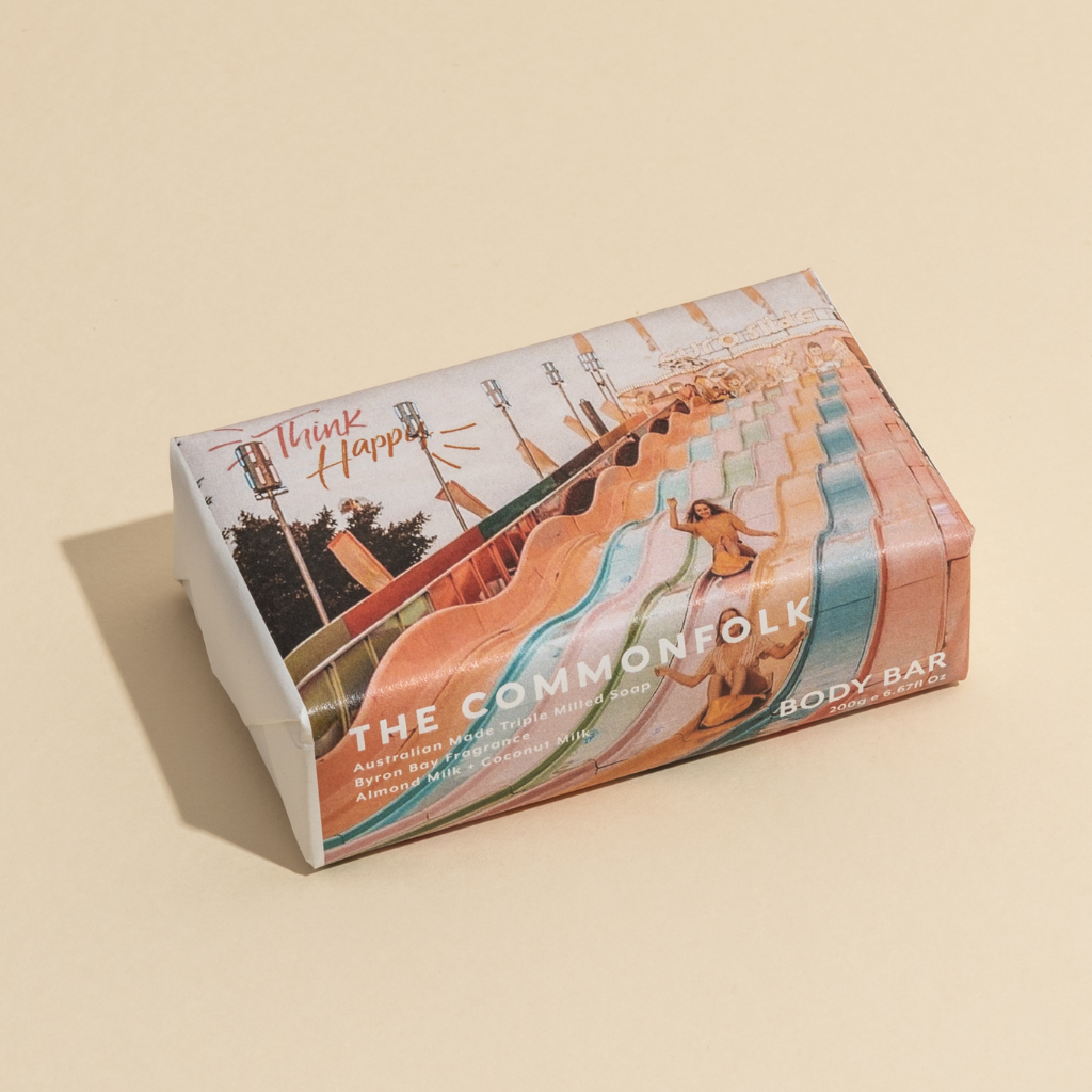 The Commonfolk 200g body bar soap, with a colorful design, is labeled 'Think Happy' on the top of the wrapper.