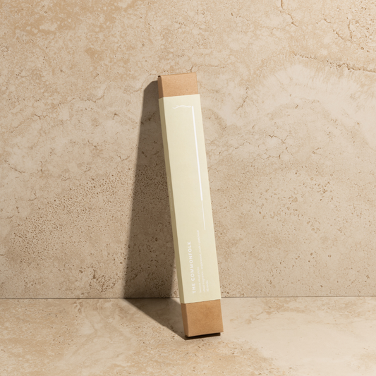 The Commonfolk scented single pack of incense ritual stick with a light-colored body and a brown tip, standing upright against a textured beige background.