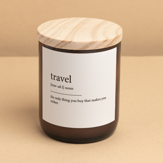 The Commonfolk scented mid-sized candle with a wooden lid and a label that reads 'travel', defined as 'the only thing you buy that makes you richer'.