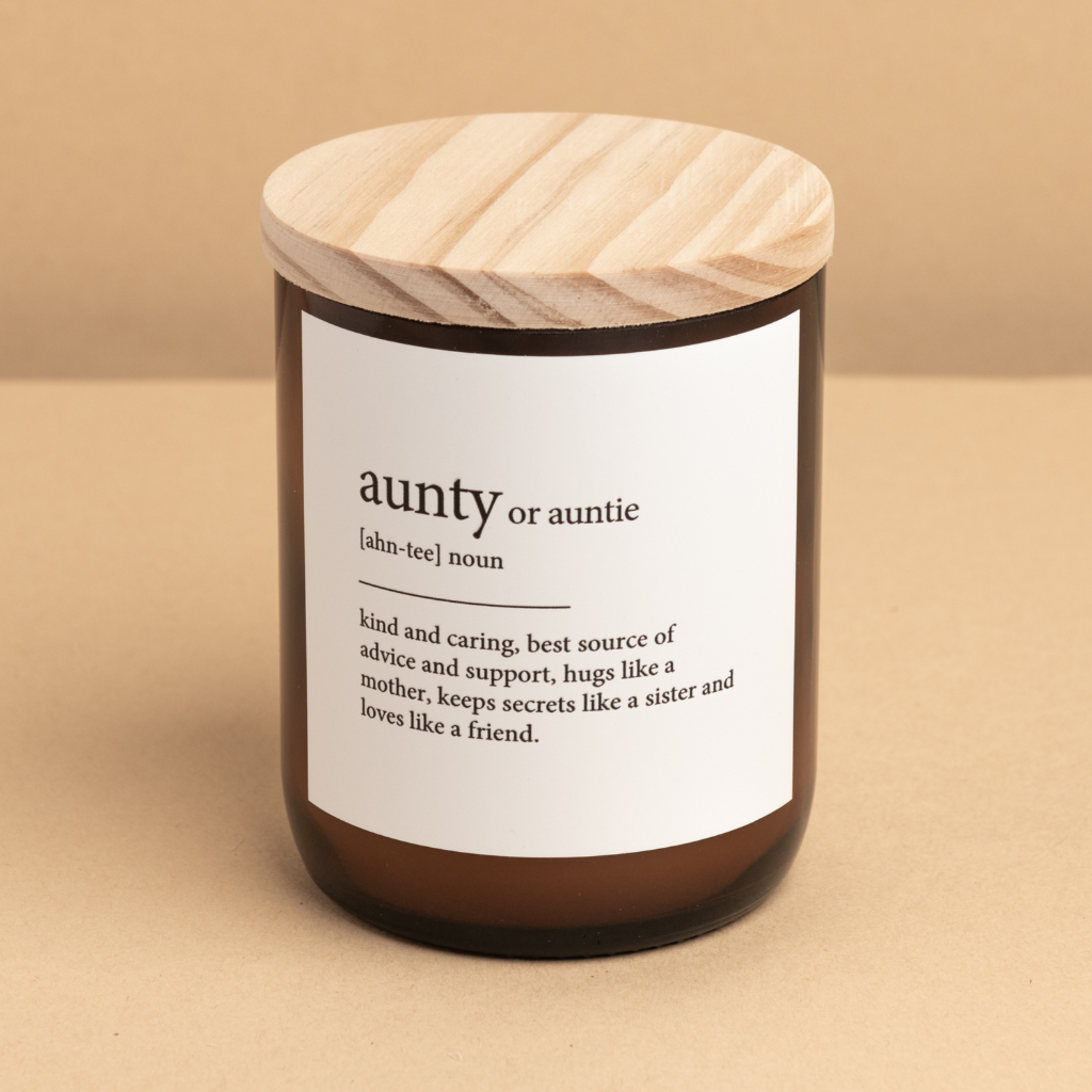 The Commonfolk scented soy and coconut wax candle in an amber jar with a wooden lid, labeled 'aunty or auntie' with a definition in quote marks.