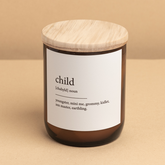 The Commonfolk scented candle with a wooden lid, the label has the word 'child' defined as 'youngster, mini me, grommy, kidlet, zen master, earthing'.