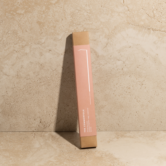 A pink pack of The Commonfolk incense ritual sticks is placed against a textured beige background.