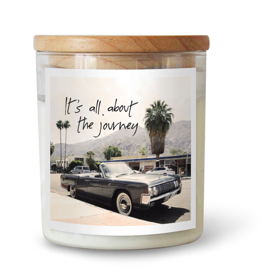 The Commonfolk scented candle features a label with a vintage car and palm trees, along with the text 'It's all about the journey.'
