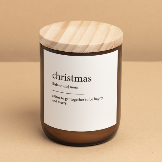 The Commonfolk scented candle with a white label that reads 'christmas', with a wooden lid on a beige background.