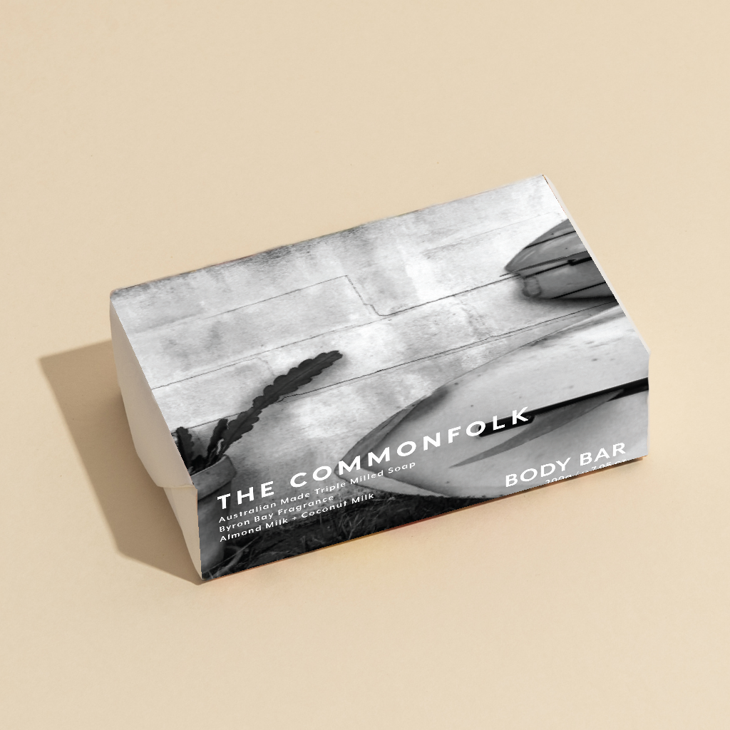 The Commonfolk 200g body bar soap features a black and white design on the wrapping, with a predominantly white background.
