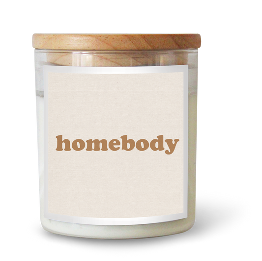 The Commonfolk scented white candle in a clear glass jar with a wooden lid, labeled 'homebody'.