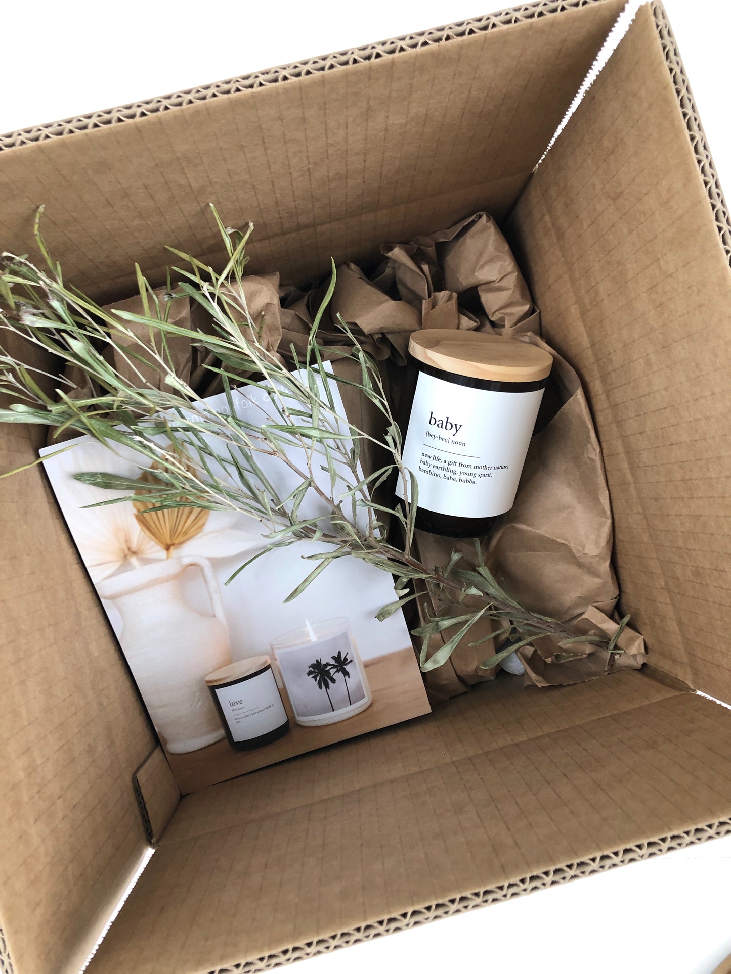 A box featuring a candle alongside a vibrant plant, creating a warm and serene decorative display.