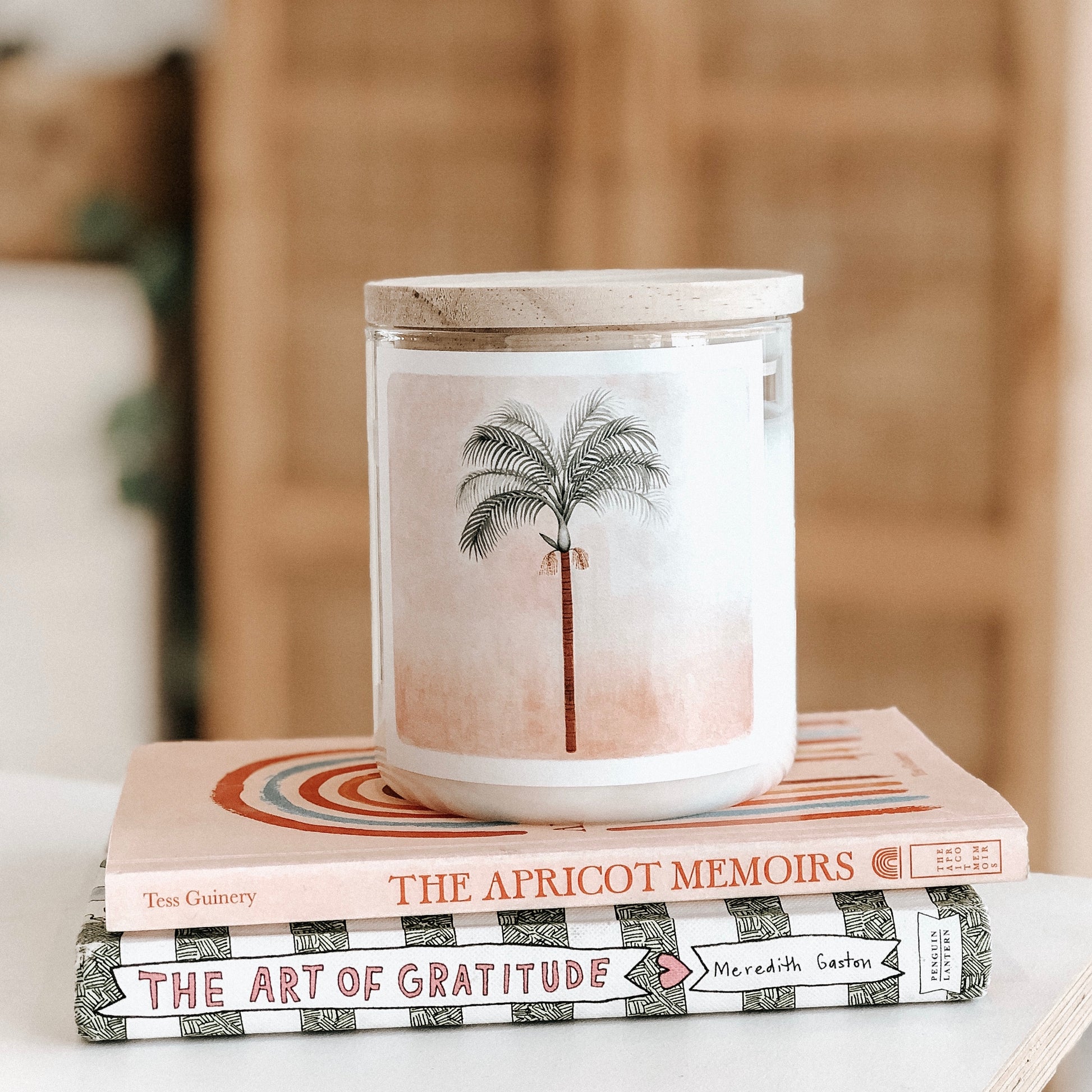 A candle placed on a stack of books atop a wooden table, creating a cozy and inviting atmosphere.