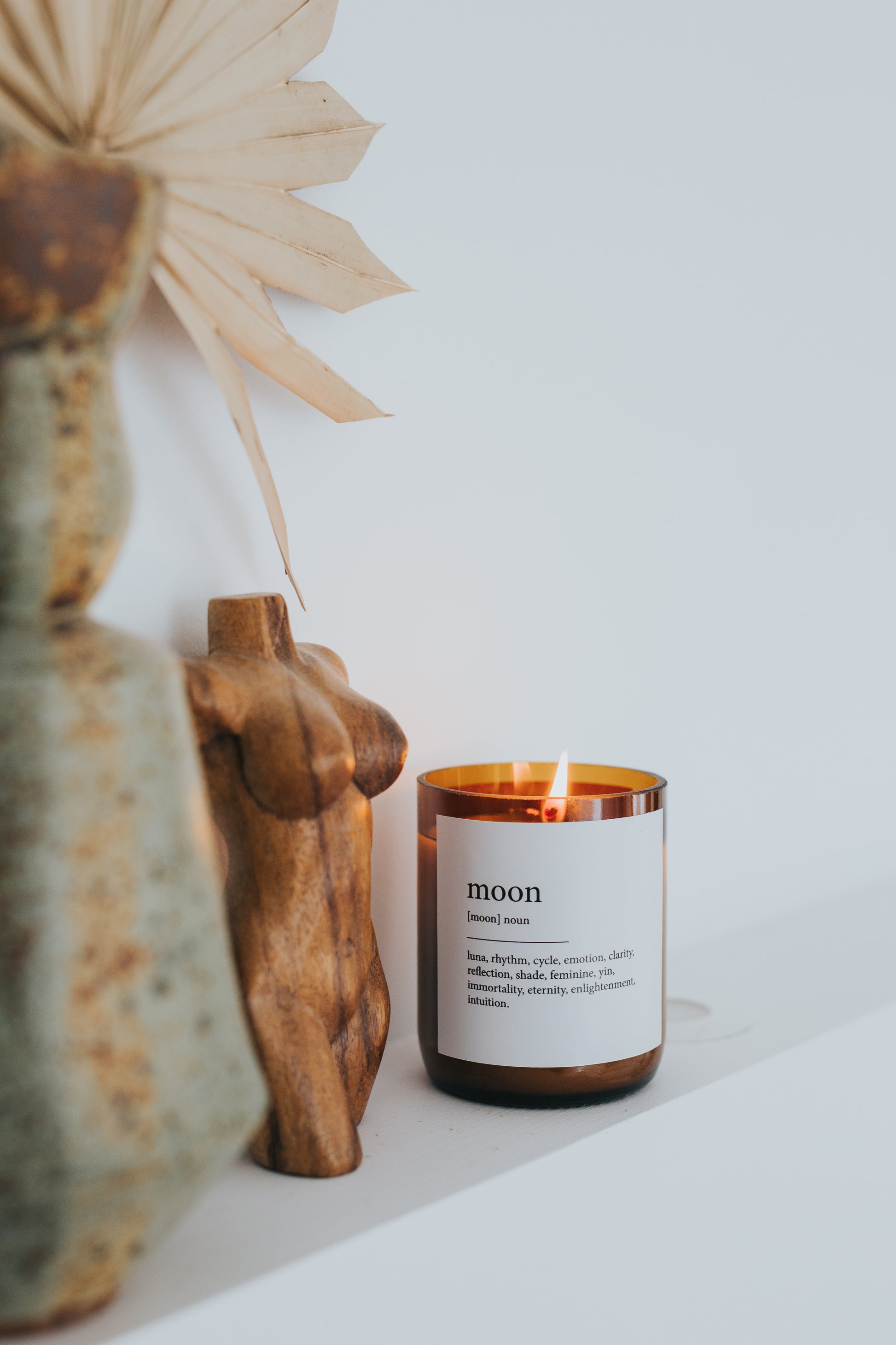A candle on a shelf beside a decorative statue, creating a serene and artistic display.