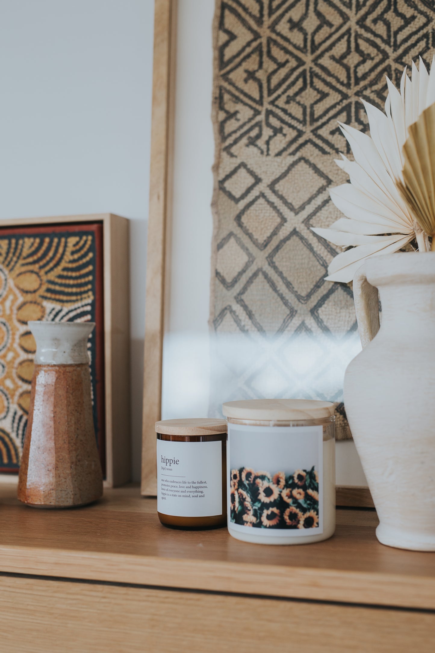 A wooden shelf displaying candles, vases, and a painting, creating a warm and inviting atmosphere.