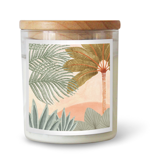 The Commonfolk scented candle comes in a clear glass jar with a wooden lid and features a label depicting an artistically rendered landscape with plants and a sunset.