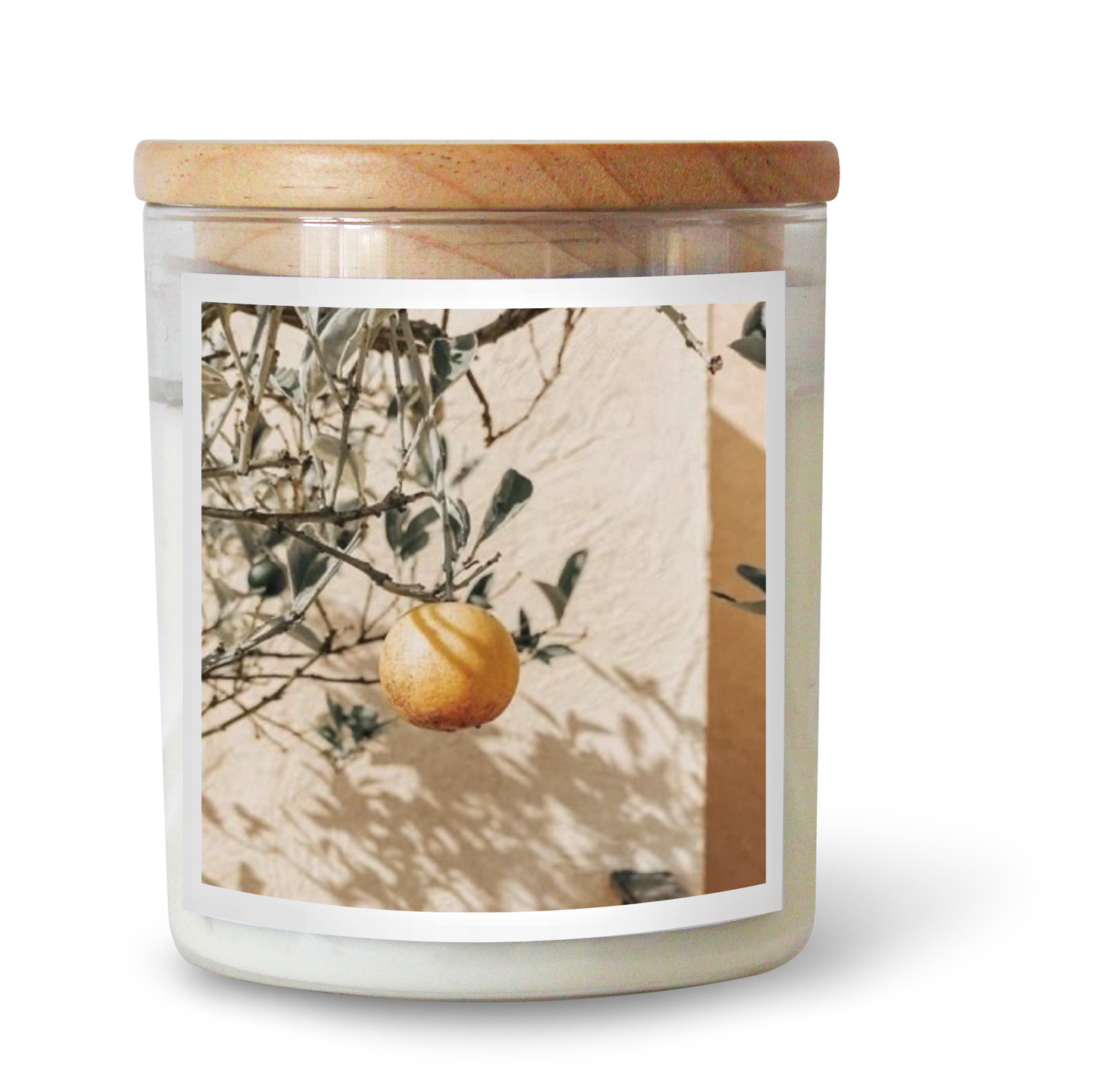 The Commonfolk scented white candle with a wooden lid and a label featuring a lemon and foliage design.