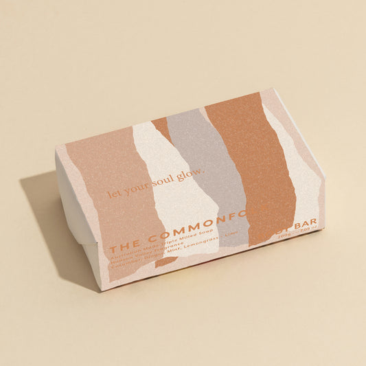 The Commonfolk 200g body bar soap features a minimalist design with shades of pink and beige, and the text 'let your soul glow' on the top.