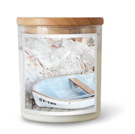 The Commonfolk scented candle features white soy wax, a wooden lid, and an image of a blue boat on the label.