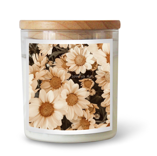 The Commonfolk scented candle is in a clear jar with a floral pattern and a 'love ya mum' text on the label, predominantly white wax, and a wooden lid.